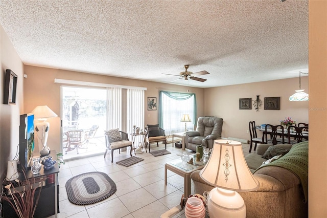 living room with light tile patterned flooring, ceiling fan, and a textured ceiling