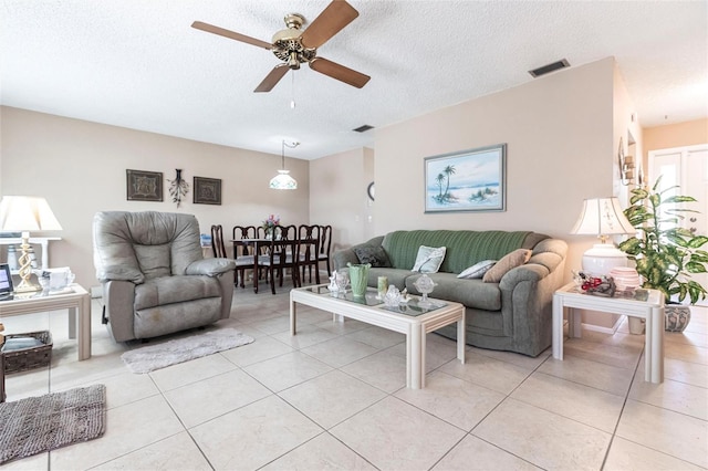 living room featuring light tile patterned flooring, ceiling fan, and a textured ceiling