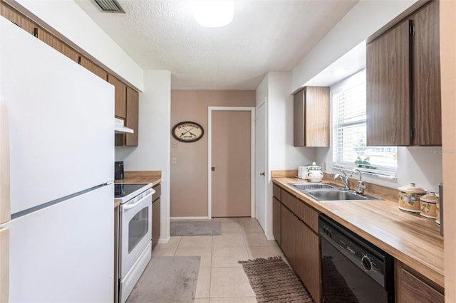 kitchen with sink, white appliances, light tile patterned floors, and a textured ceiling