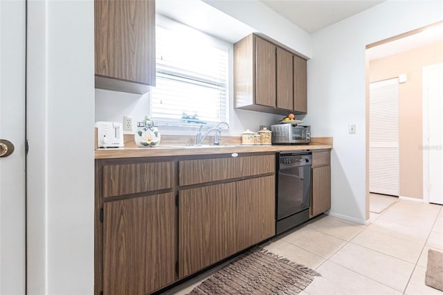 kitchen with light tile patterned flooring, black dishwasher, and sink