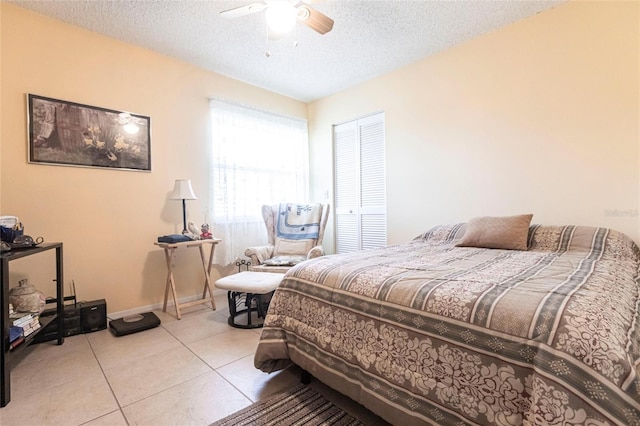 tiled bedroom with ceiling fan and a textured ceiling