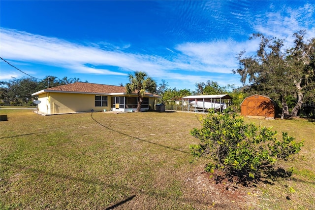 back of property with a shed, a yard, and a carport