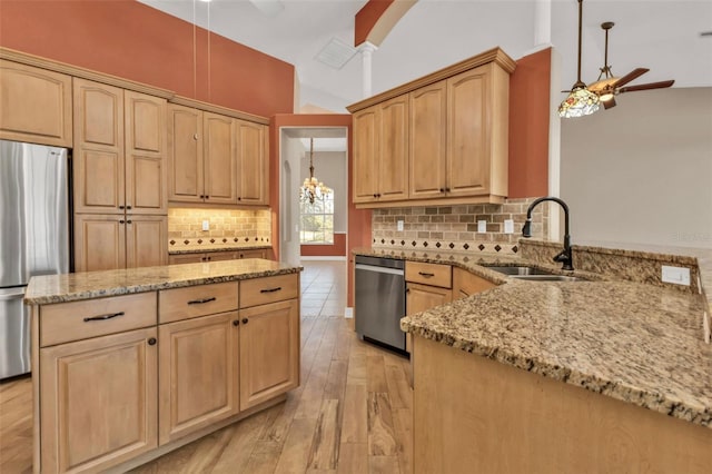 kitchen featuring stainless steel appliances, a sink, a ceiling fan, and light stone countertops