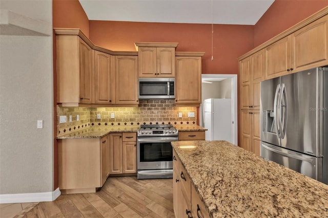 kitchen with tasteful backsplash, appliances with stainless steel finishes, and light stone counters