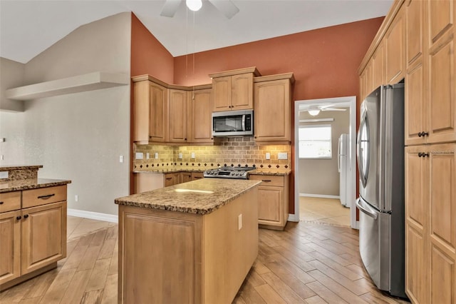 kitchen featuring vaulted ceiling, appliances with stainless steel finishes, backsplash, and a ceiling fan