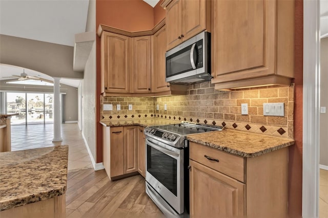 kitchen with decorative columns, light wood-style flooring, decorative backsplash, appliances with stainless steel finishes, and ceiling fan