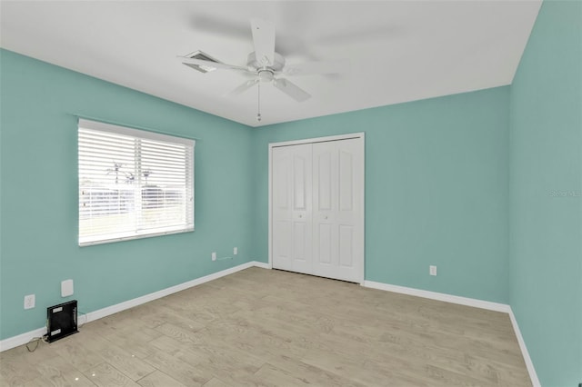 unfurnished bedroom featuring light wood-style floors, baseboards, and a closet