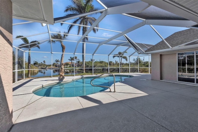 pool with glass enclosure, a patio area, and a water view