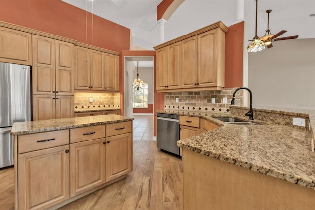kitchen with a ceiling fan, light stone counters, appliances with stainless steel finishes, and a sink
