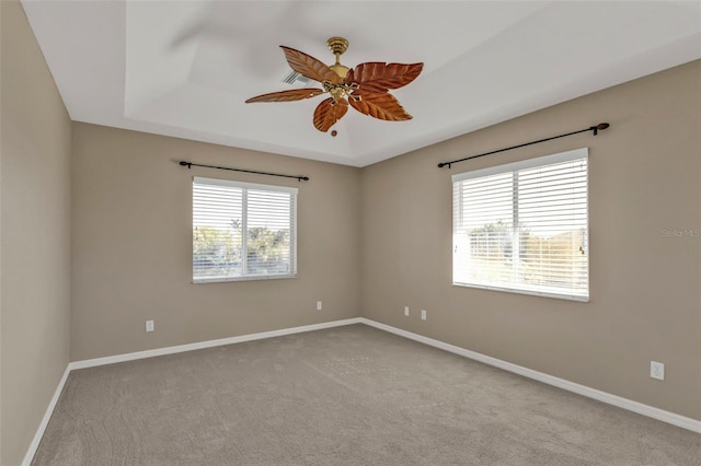 unfurnished room with ceiling fan, baseboards, carpet, and a tray ceiling