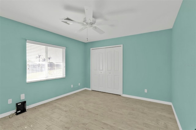 unfurnished bedroom featuring a closet, a ceiling fan, baseboards, and light wood-type flooring