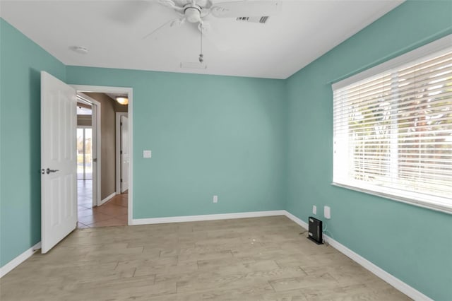 spare room featuring visible vents, a ceiling fan, and baseboards