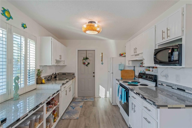 kitchen with white cabinetry, light stone counters, and white appliances