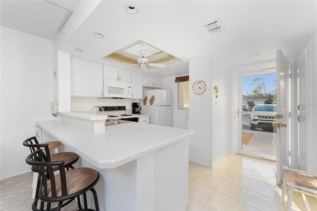 kitchen featuring sink, white appliances, a breakfast bar, white cabinets, and kitchen peninsula