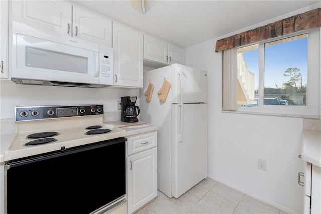 kitchen with light tile patterned floors, white appliances, and white cabinets