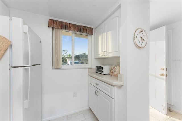 kitchen featuring white cabinetry, light tile patterned floors, and white fridge