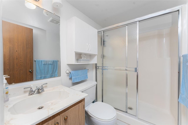 bathroom featuring vanity, toilet, and a shower with shower door