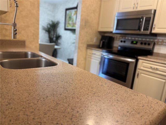 kitchen featuring sink, stainless steel appliances, light stone countertops, white cabinets, and decorative backsplash