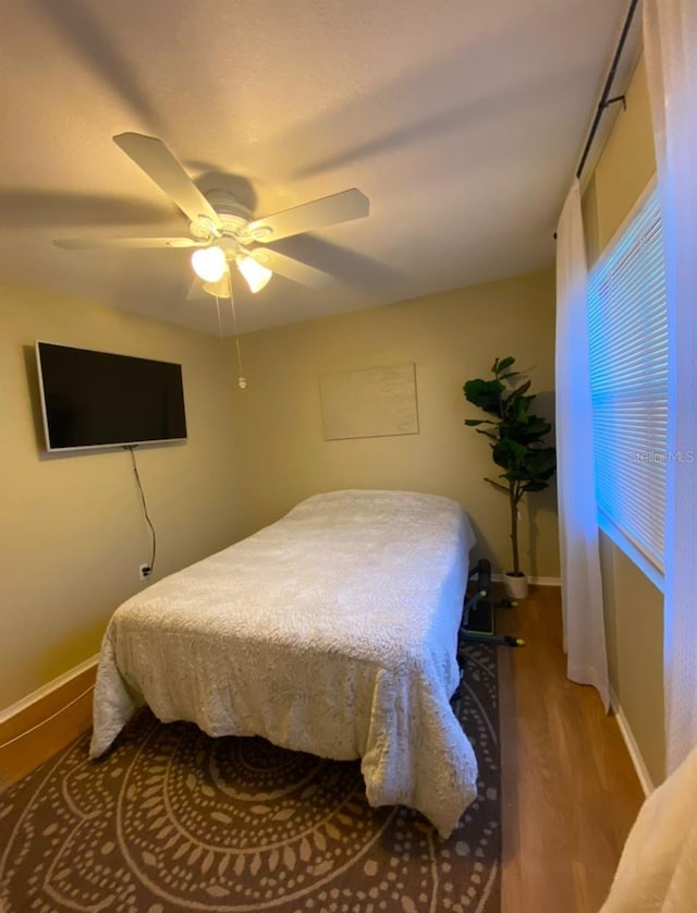 bedroom featuring a ceiling fan, baseboards, and wood finished floors