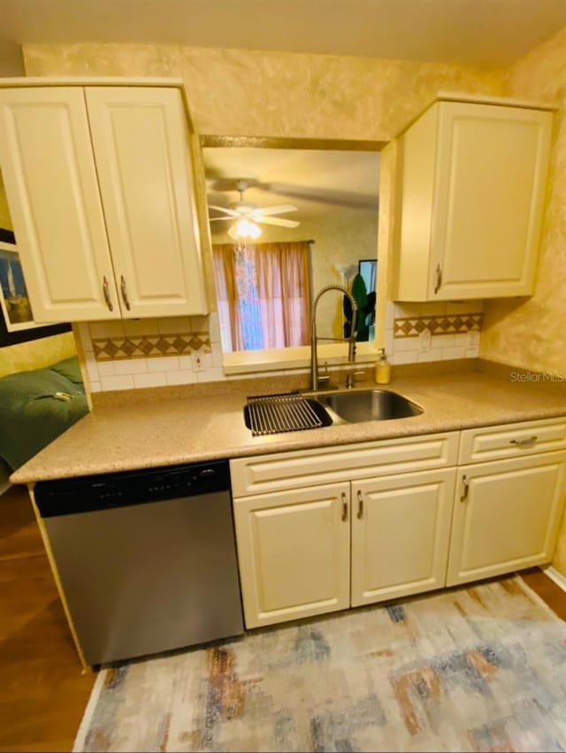 kitchen with a sink, light wood-style floors, light countertops, stainless steel dishwasher, and backsplash