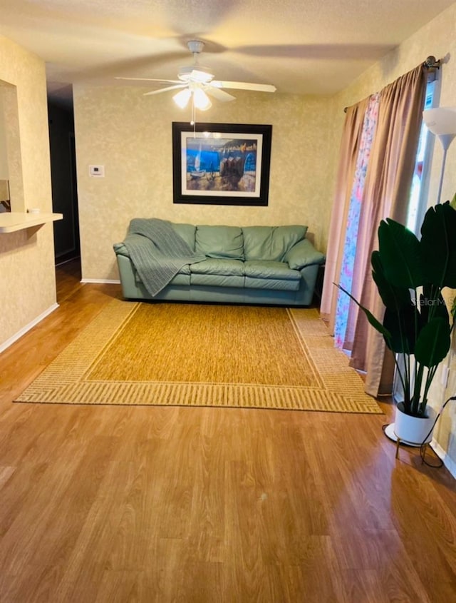 unfurnished living room featuring a ceiling fan, a textured ceiling, baseboards, and wood finished floors