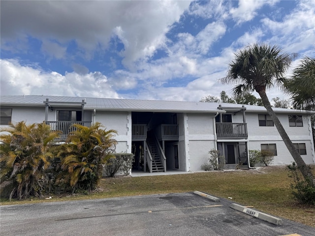 view of property with uncovered parking and stairs