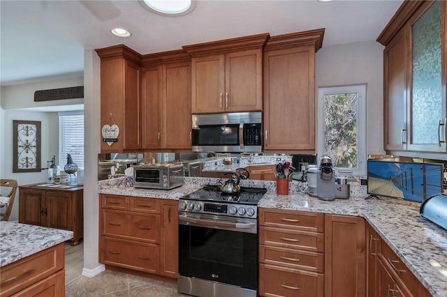 kitchen with appliances with stainless steel finishes, light stone countertops, and light tile patterned floors