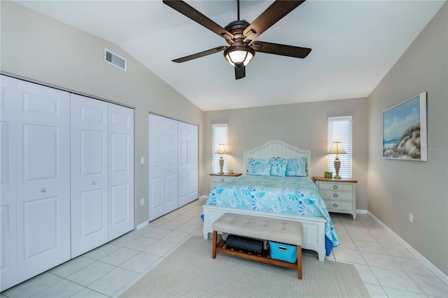 bedroom with multiple closets, lofted ceiling, light tile patterned floors, and ceiling fan