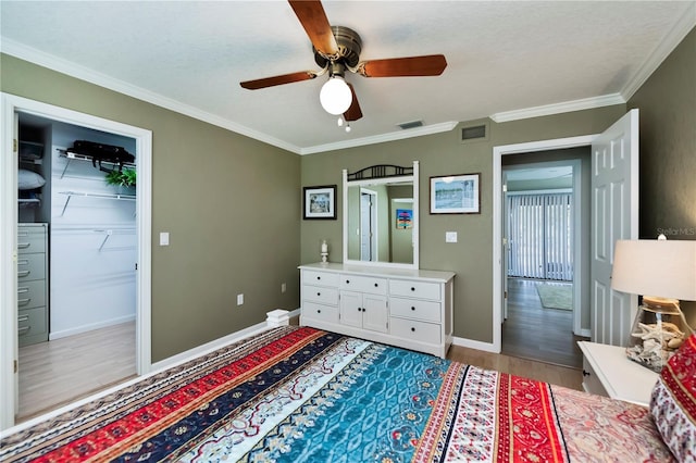 bedroom featuring ornamental molding, a spacious closet, ceiling fan, and light hardwood / wood-style flooring