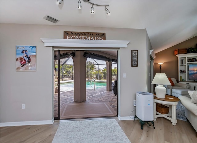 entryway with lofted ceiling, track lighting, and light hardwood / wood-style flooring