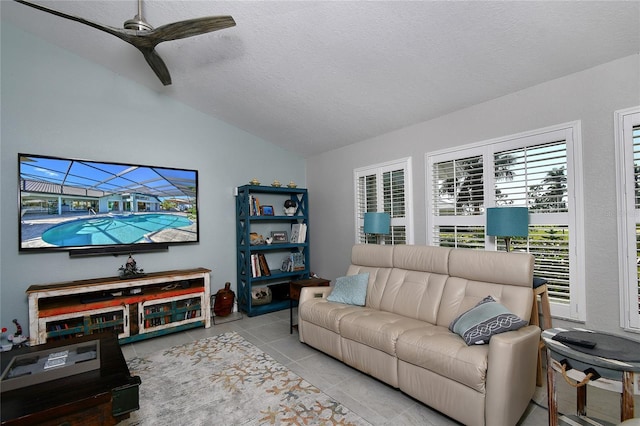 living room featuring light tile patterned flooring, ceiling fan, vaulted ceiling, and a textured ceiling