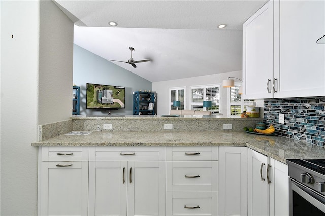 kitchen with white cabinetry, light stone counters, lofted ceiling, and kitchen peninsula