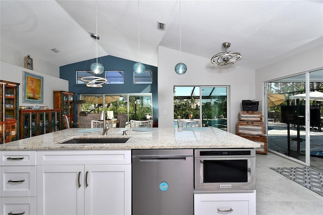 kitchen with vaulted ceiling, appliances with stainless steel finishes, pendant lighting, white cabinets, and light stone counters