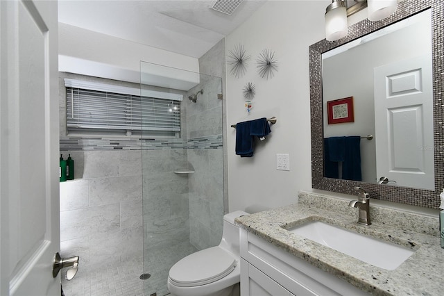 bathroom featuring tiled shower, vanity, and toilet