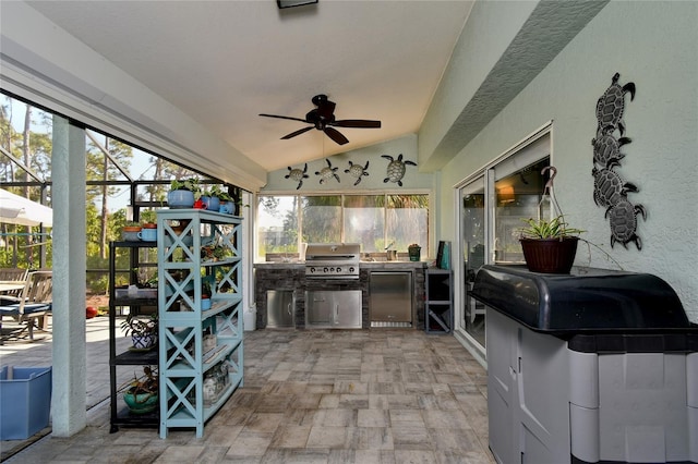 view of patio featuring ceiling fan, an outdoor kitchen, grilling area, and glass enclosure