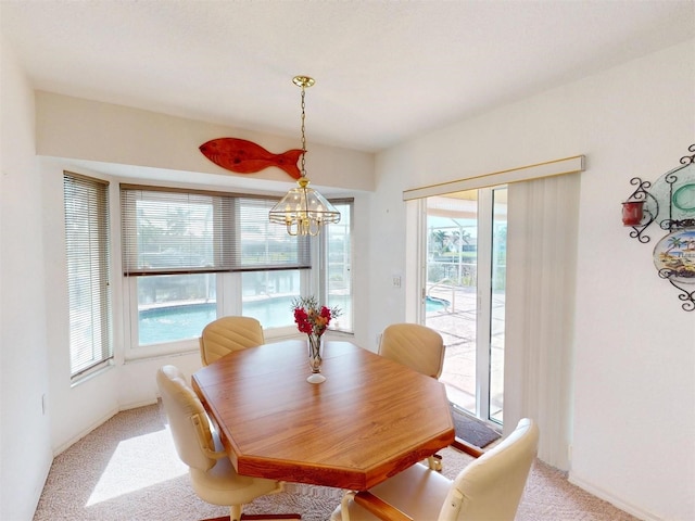 carpeted dining room featuring a wealth of natural light and an inviting chandelier