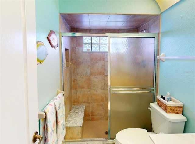 bathroom featuring a shower with door and toilet