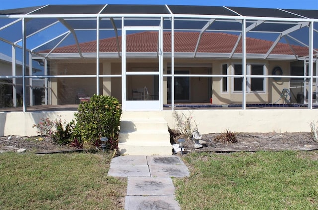 rear view of house featuring a yard and glass enclosure