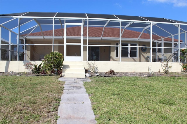 back of house with glass enclosure and a lawn