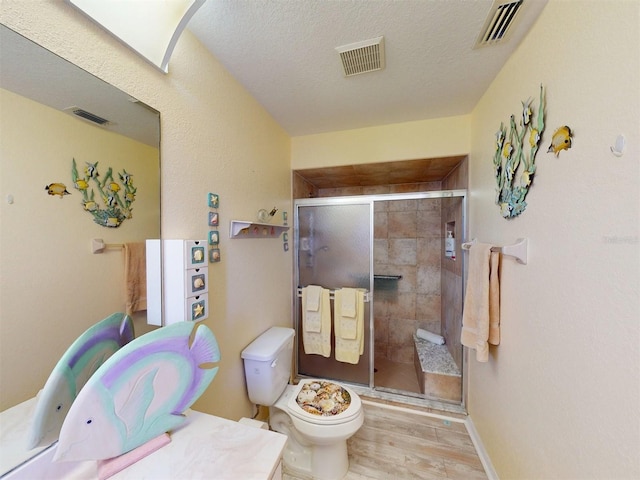 bathroom featuring hardwood / wood-style flooring, toilet, an enclosed shower, and a textured ceiling