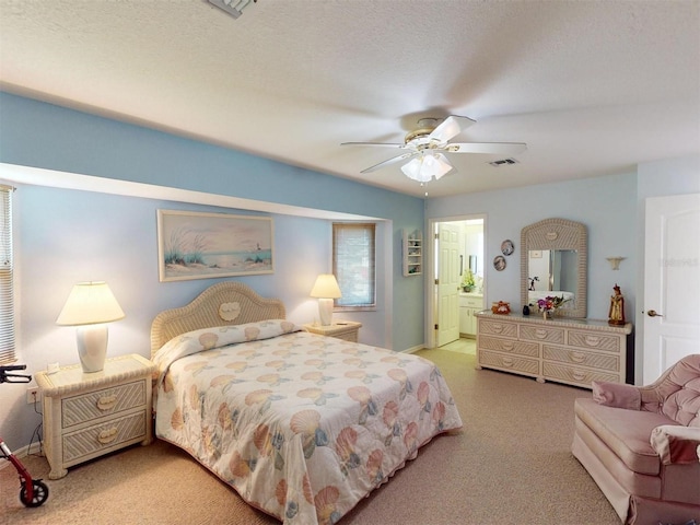 bedroom with ceiling fan, light colored carpet, ensuite bathroom, and a textured ceiling