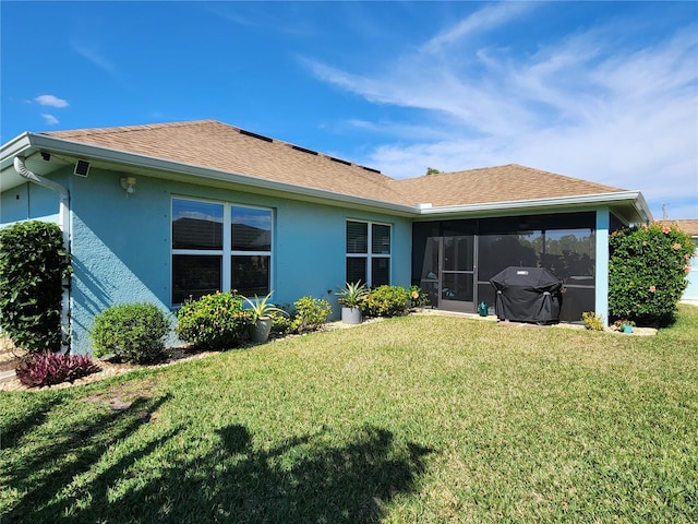 rear view of house featuring a sunroom and a lawn