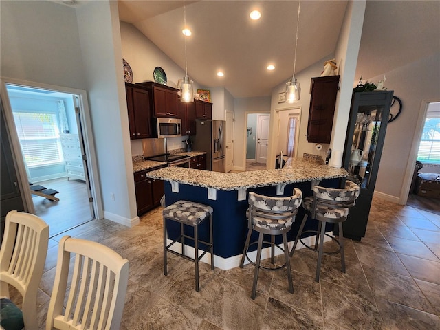 kitchen with a breakfast bar area, appliances with stainless steel finishes, kitchen peninsula, a wealth of natural light, and pendant lighting