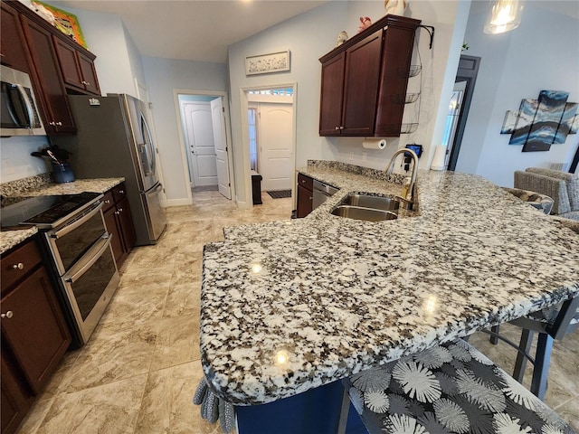 kitchen featuring sink, a kitchen bar, kitchen peninsula, and appliances with stainless steel finishes