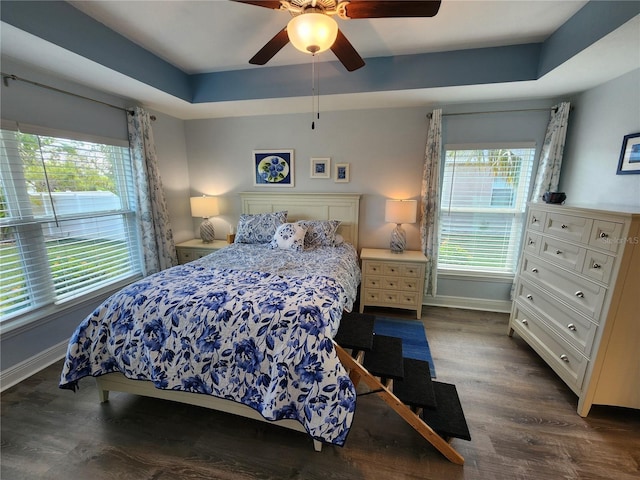 bedroom featuring dark wood-type flooring, ceiling fan, and a raised ceiling