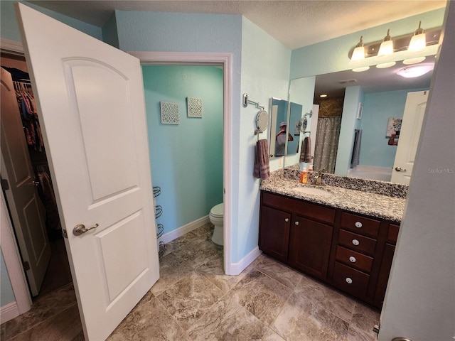 bathroom with vanity, walk in shower, a textured ceiling, and toilet