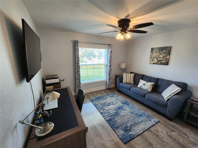 living room featuring ceiling fan, hardwood / wood-style floors, and a textured ceiling