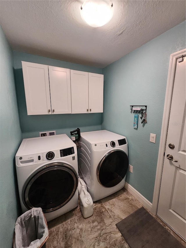 laundry room with cabinets, washer and dryer, and a textured ceiling