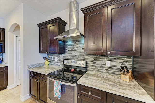 kitchen with tasteful backsplash, stainless steel electric stove, light stone countertops, and wall chimney exhaust hood