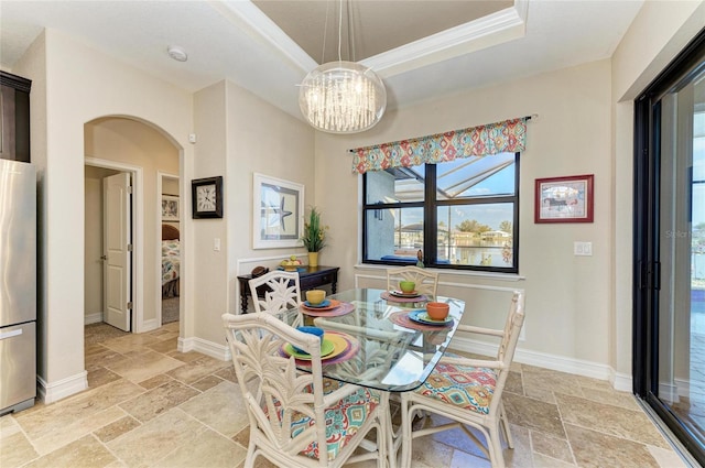 dining room featuring an inviting chandelier, a tray ceiling, and ornamental molding